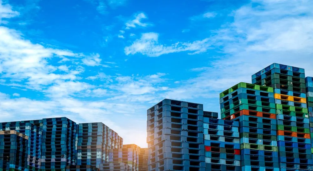 Pallets coloridos empilhados ao ar livre, demonstrando o que é pallet na logística e no transporte.